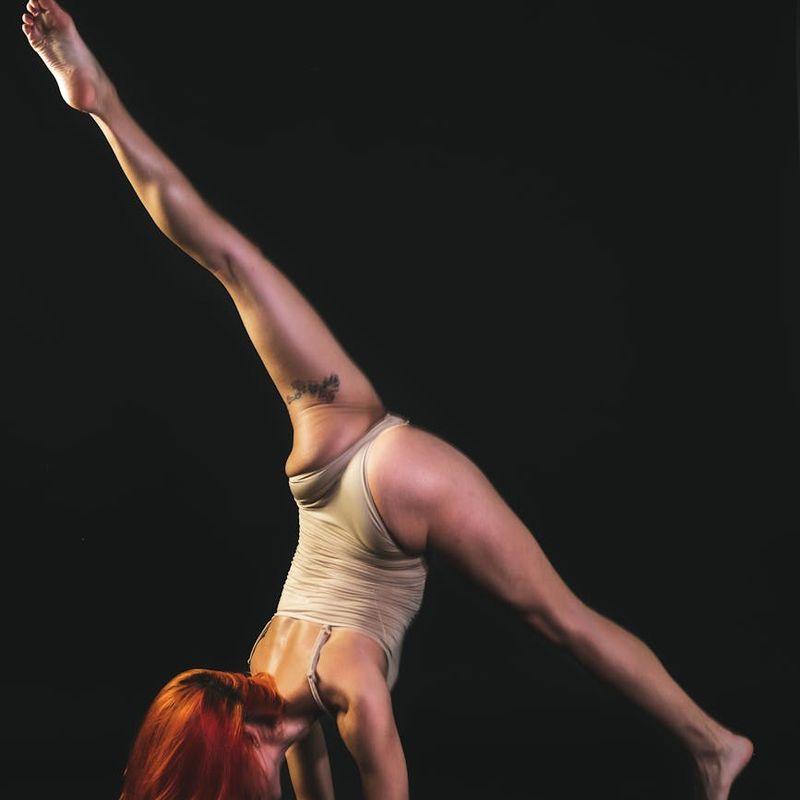 Person in a dynamic yet graceful yoga pose in a spacious studio.